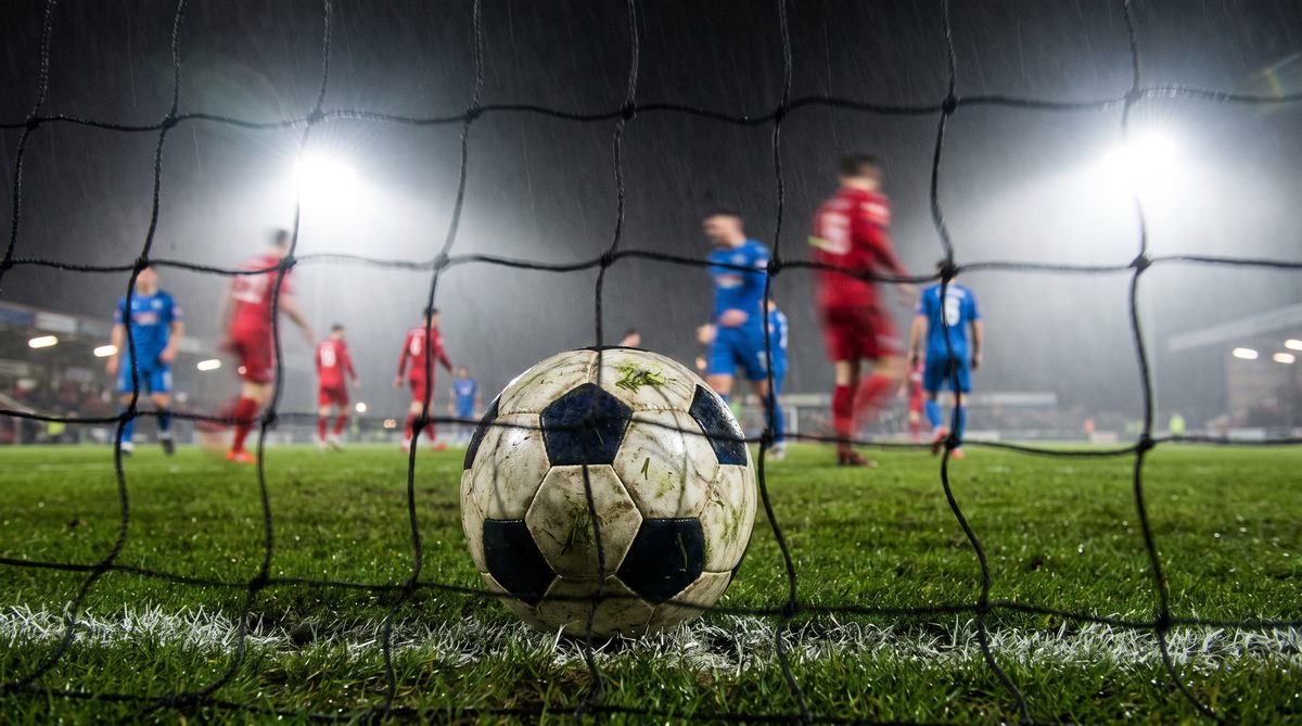 Close-up of a soccer ball resting on the goal line inside a stadium net